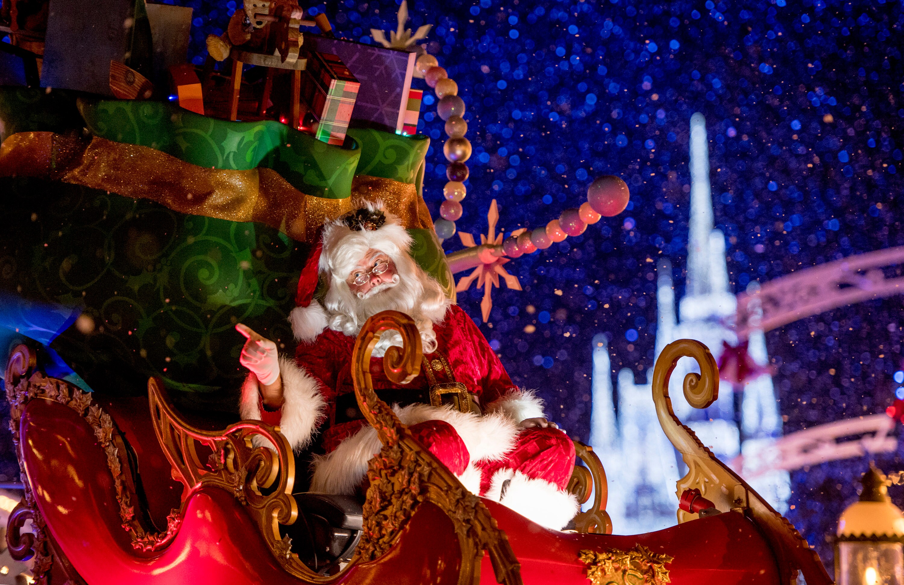 Mickey and Minnie Mouse dressed in holiday attire, standing beside a Christmas tree and presents